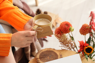 Female hands with cup of coffee at home on autumn day, closeup