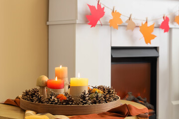 Tray with burning candles and autumn decor on table in room, closeup