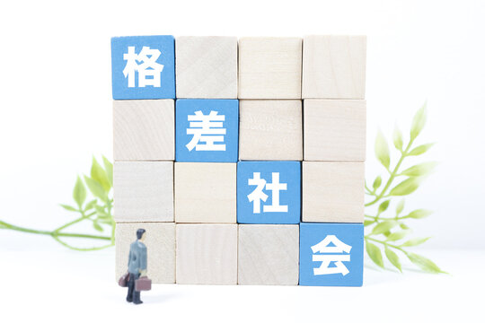 格差社会の壁とビジネスマンの人形。経済的不平等を象徴するイメージ。