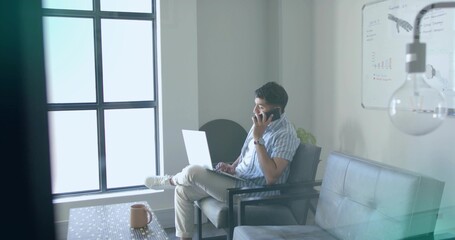 Holding smartphone businessman typing on laptop in lounge by grid window, with mug on wood table