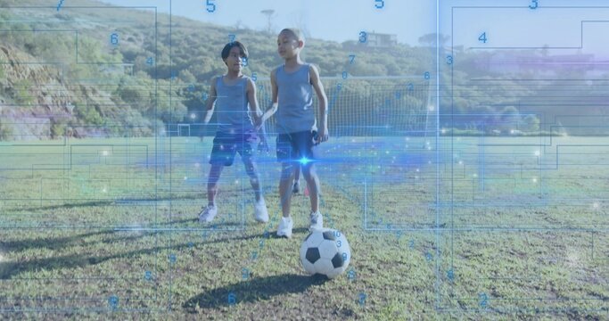 Two boys scanning digital data overlays on grassy center field, with soccer ball by goal net