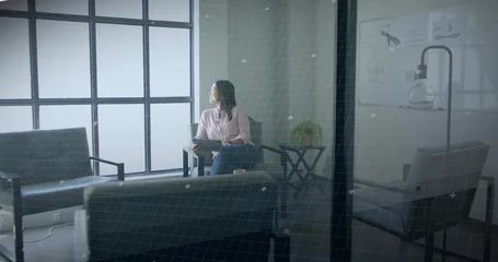 Fotobehang Sportwinkel Observing Asian woman sitting thoughtfully in office lounge area, with tablet device and whiteboard  © vectorfusionart