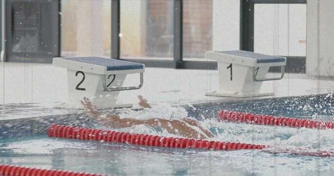 Diving male swimmer creating underwater splashes in lap pool at aquatic center, with red lane ropes