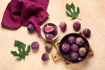 Bowls with fresh ripe figs on beige background
