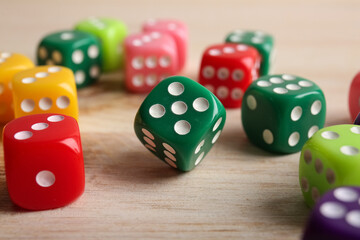 Colorful game dices on wooden background, closeup