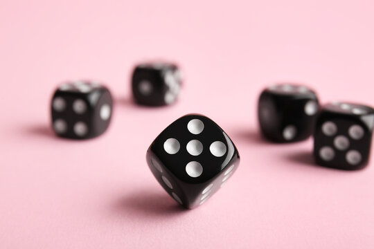 Black game dices on pink background
