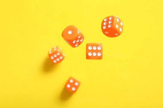 Flying orange game dices on yellow background