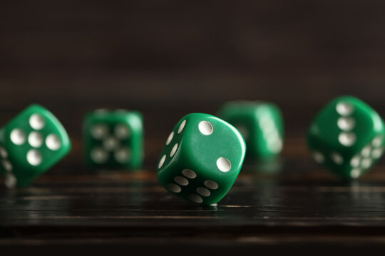 Green game dices on wooden background, closeup