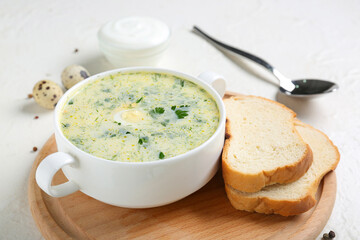 Pot of tasty green borscht with eggs, sour cream and bread slices on white background