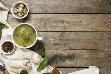 Bowl of tasty green borscht with ingredients on wooden background