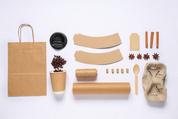Composition with cup of coffee beans, spices and delivery paper bag on white background