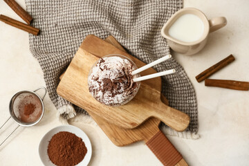 Glass of cold cocoa drink with whipped cream and cinnamon on white background