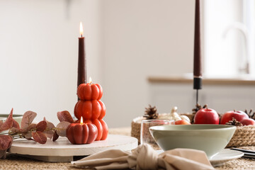 Autumn table setting with burning candles in kitchen, closeup
