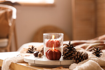 Tray with fir cones and burning candles on table in living room, closeup