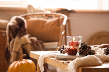 Tray with fir cones and burning candles on table in living room, closeup