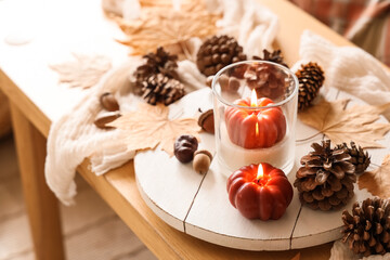 Tray with fir cones and burning candles on table in living room, closeup