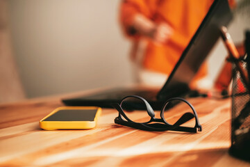 Workspace setup featuring glasses and smartphone in a minimalistic environment during daytime