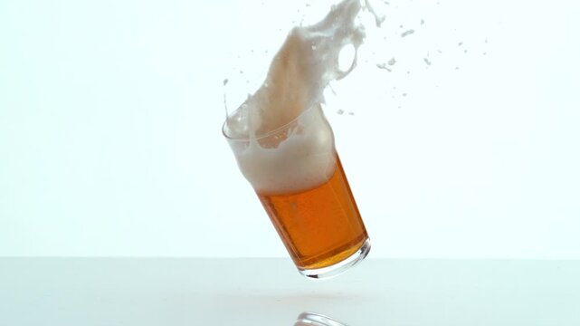 Glass of Beer falling and spilling in slow motion