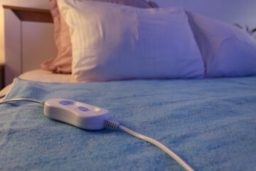 Modern electric heating pad on bed in room at night, closeup