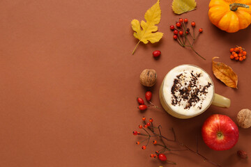 Composition with mug of coffee and autumn decor on brown background