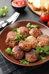 Delicious patties with parsley in bowl on grey textured table, closeup