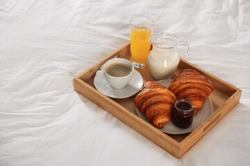 Tray with delicious breakfast on bed in hotel room, closeup. Space for text