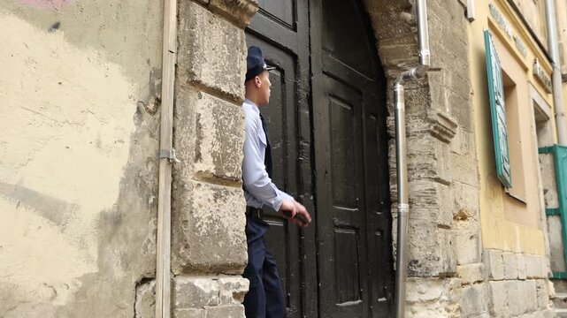 Police officer with gun running and hiding near building on city street