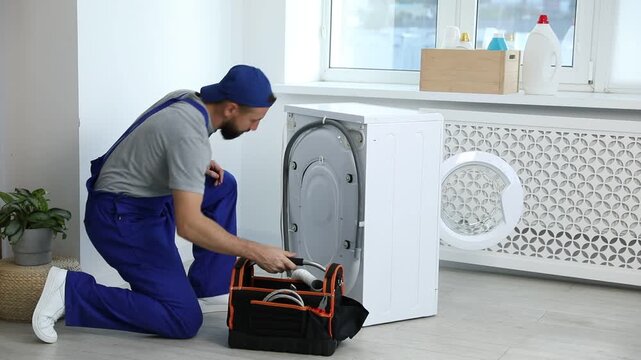 Professional repairman fixing broken washing machine indoors