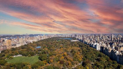 Aerial view of a park in a large city as the sun sets, painting the sky.
