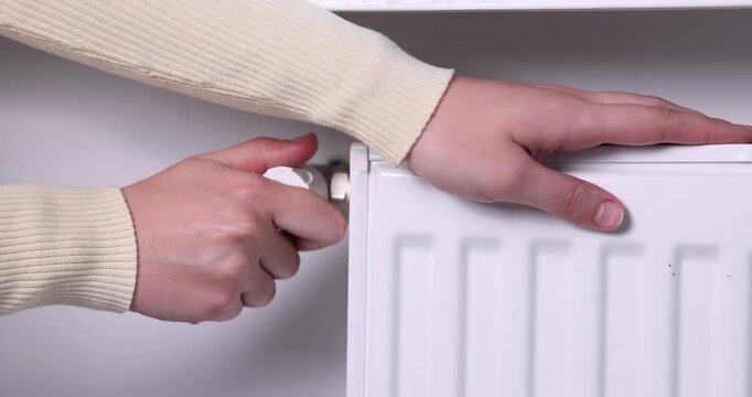 Woman adjusting temperature of radiator indoors, closeup