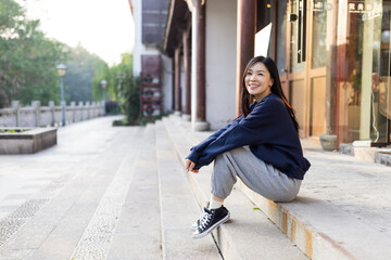 Fototapeta premium Young woman sitting on outdoor steps smiling in urban setting
