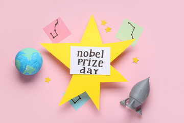 Composition with star, planet, rocket and NOBEL PRIZE DAY greeting card on pink background. Nobel...