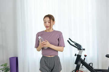 Young woman at home enjoys healthy activity, holding water bottle after exercise, people focusing...