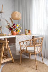 Books and pumpkin with autumn bouquet on table near window in interior of living room