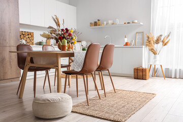 Table, chairs and pumpkin with autumn bouquet in interior of kitchen