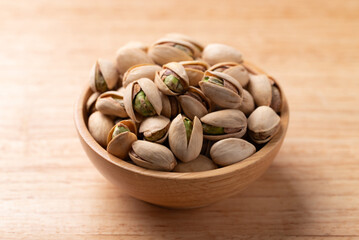 Roasted Pistachio nuts in a bowl on wooden background