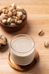 Pistachio milk in glass with pistachio nuts on wooden background, Alternative milk made from plant, Dairy free