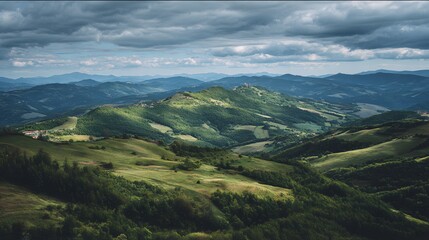 Fototapeta premium Rolling green hills and verdant valleys stretch beneath a dramatic, overcast sky.