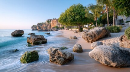Serene Tropical Island Shoreline with Gentle Waves Rolling Over Pebbles and Rocks Under Warm Sunlight With Lush Green Trees and Buildings in the Background