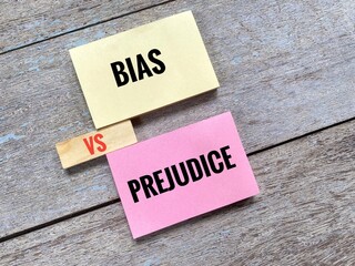 Bias Vs Prejudice on colorful sticky notes and wooden block against wood background. 
