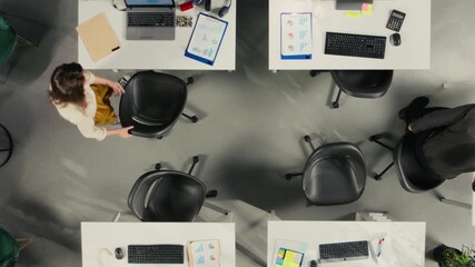 Top down view zoom out of staff in office discuss business strategy and market research. Diverse coworkers evaluate documents and diagrams to align goals, targets and performance metrics. Camera A. - Powered by Adobe