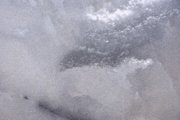 Gray marble, polished natural stone surface with black inclusions throughout, close-up.