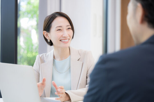 保険や企画の営業をするスーツの女性、会社で商談や打ち合わせするビジネスマンの男女2人　