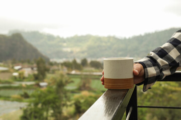 Holding a ceramic cup while admiring the scenic landscape