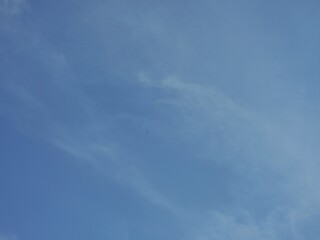 A bluish sky background with a pattern of soft white clouds. Full frame of a soft cloudy sky.