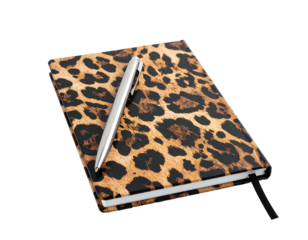 Leopard print notebook with a silver pen on top, angled view, set against a black background