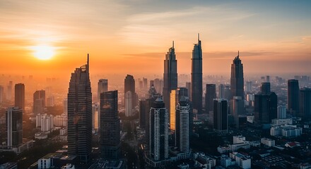 Obraz premium Stunning panoramic view of a modern city skyline at sunset with vibrant orange and yellow sky.
