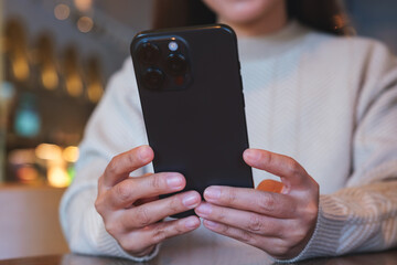 Closeup image of a woman holding and using mobile phone