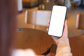 Fotobehang Muziek Mockup image of a woman holding and using mobile phone with blank desktop screen in cafe  © Farknot Architect