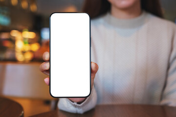 Mockup image of a woman holding and showing a mobile phone with blank white screen